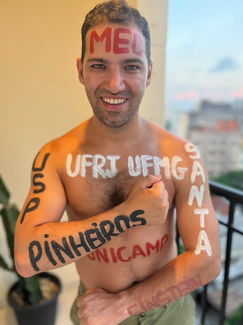 Lucas Baraças comemorando as aprovações em medicina, com os nomes das universidades pintados no corpo